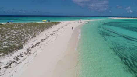 Drone-shot-man-walking-alone-on-white-sand-beach-caribbean-island-cayo-de-agua,-Los-Roques