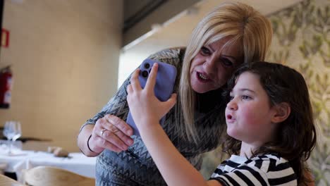 positive woman and girl taking selfie on smartphone