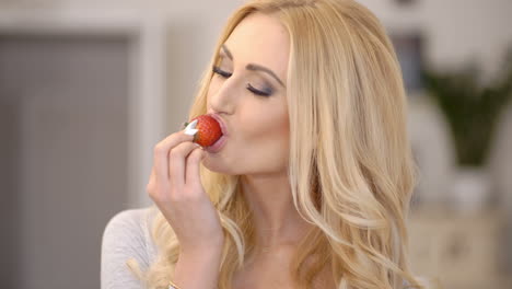 healthy attractive blond woman eating a strawberry