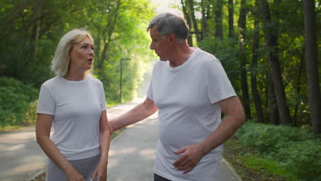 una pareja mayor caminando y hablando en un parque.