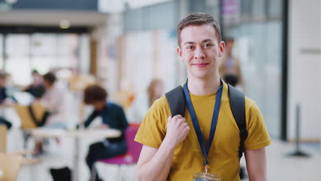 portrait of smiling male college student in busy communal campus building