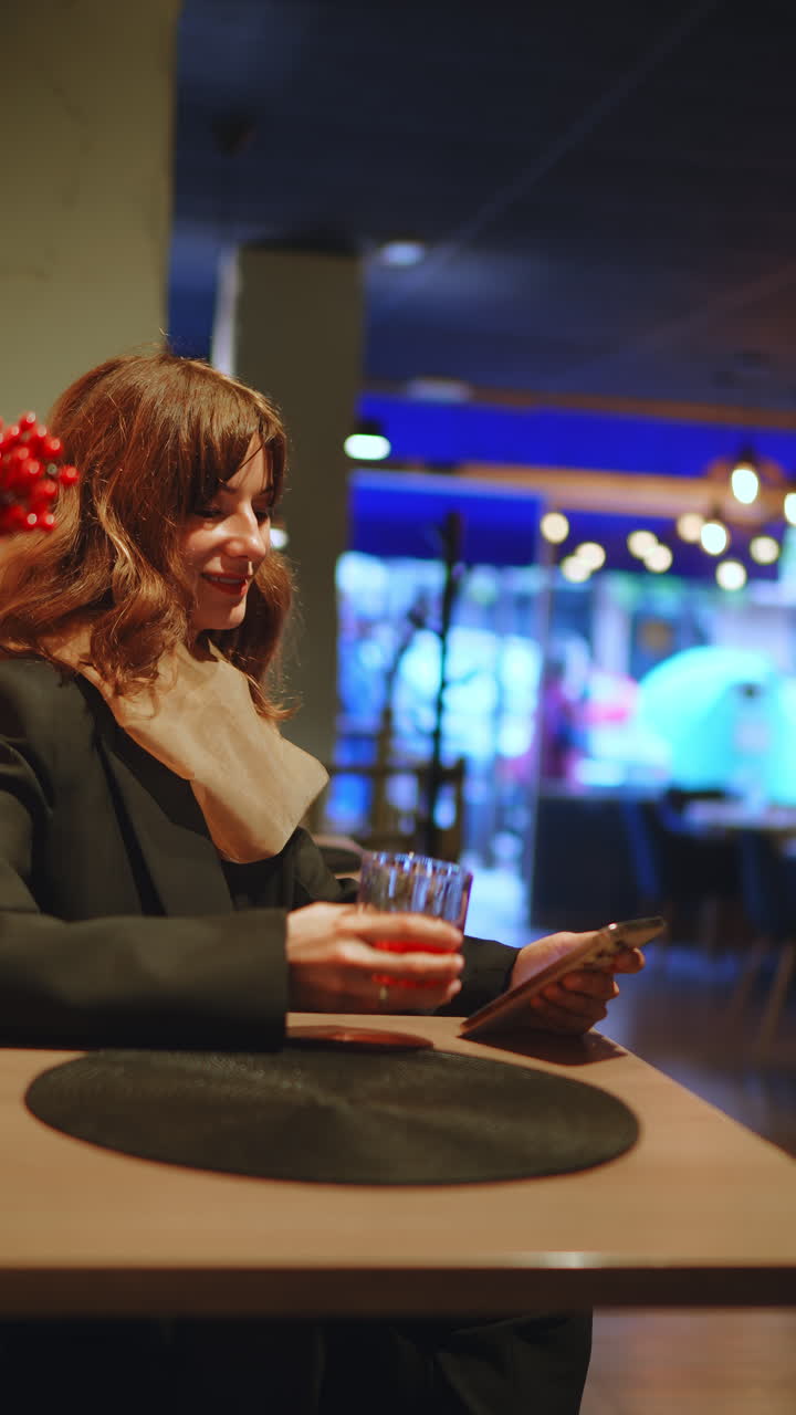 Young Woman Drinking and Using Smartphone in a Cafe