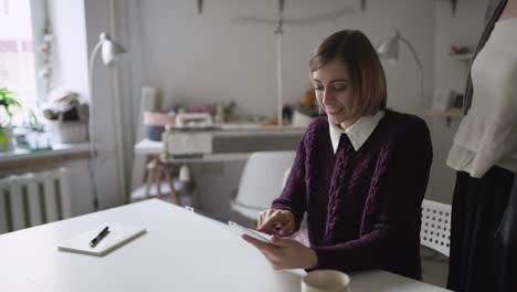 Mujer-Joven-Usando-Una-Tableta-Sentada-A-La-Mesa-En-Casa