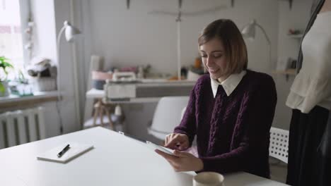 mujer joven usando una computadora tableta sentada en la mesa en casa