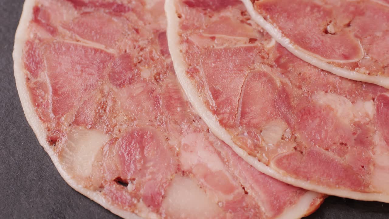 black bull sausage ham, tongue pork dry-cured sausage on a black background, traditional spanish delicatessen food, close up.