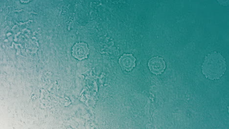 aerial rotate down over frozen lake showing circular patterns on ice