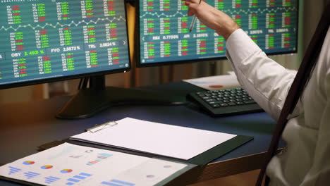 Close-up-of-stock-broker-taking-notes-on-clipboard