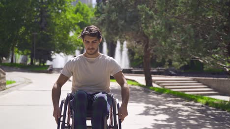 Young-disabled-man-walking-down-the-street-with-his-wheelchair.