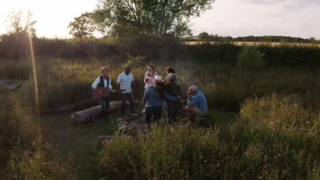 Drone-Shot-Of-Mature-Friends-Standing-Around-Fire-Singing-Songs-At-Outdoor-Campsite