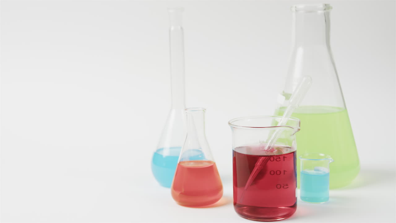 líquidos de color en frascos sobre fondo blanco con espacio para copiar, cámara lenta