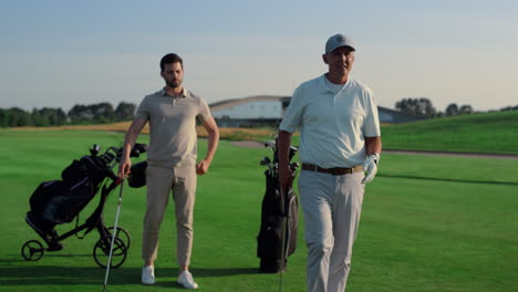 son father play golf course outside. two men talking sport hobby on summer field