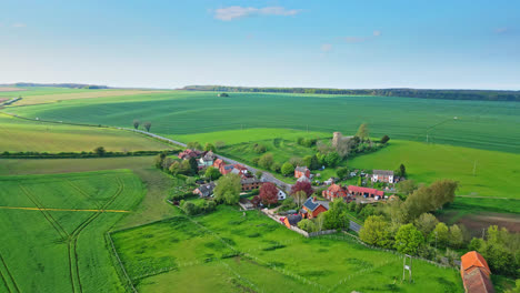 aerial drone view displays burwell village, former medieval market town—country fields, ancient red brick homes, and the idle saint michael parish church on lincolnshire's wold hills