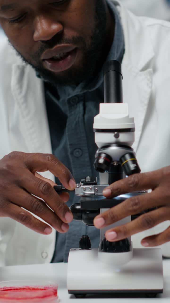 Video verticale: ricercatore che analizza campioni genetici con apparecchiature microscopiche ad alta tecnologia