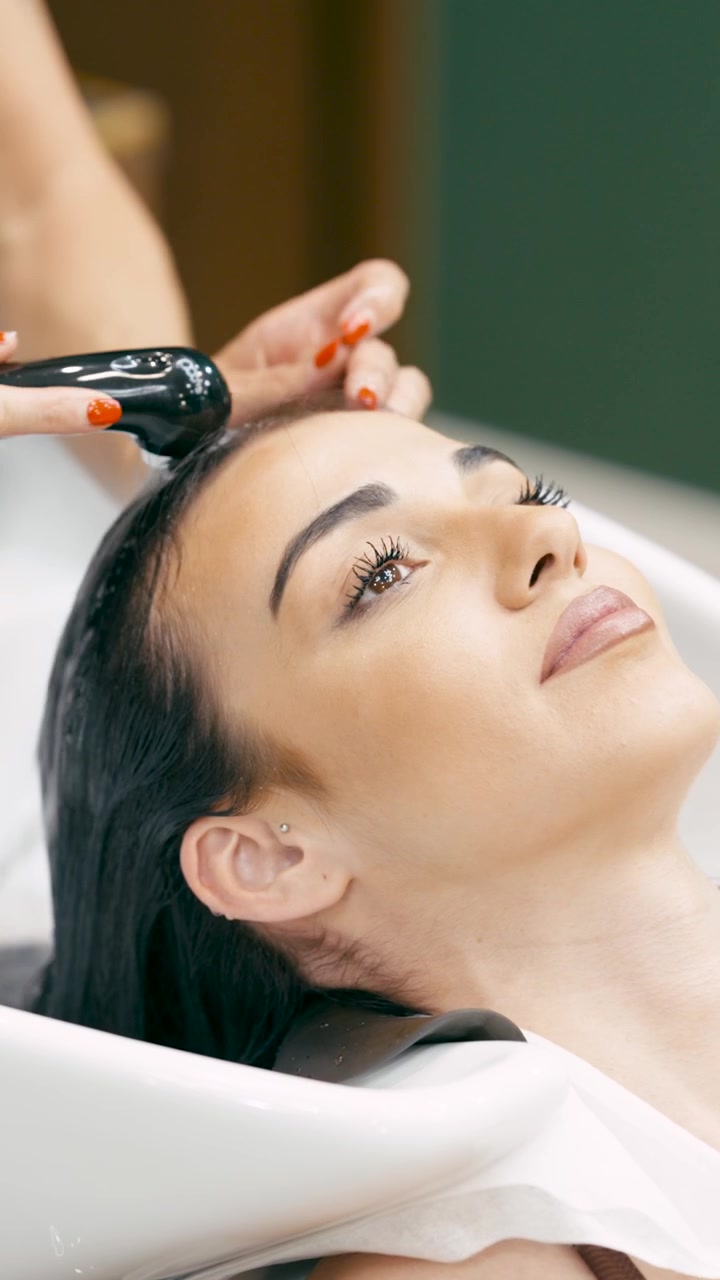 Cabeleireiro lavando o cabelo de uma jovem no lavatório do salão