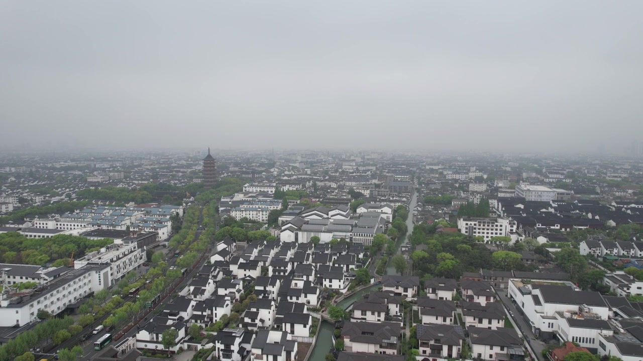Letecký záběr z přeletu kanálu Suzhou nad obytnou oblastí směrem k Severní pagodě za zataženého šedého dne, Čína.