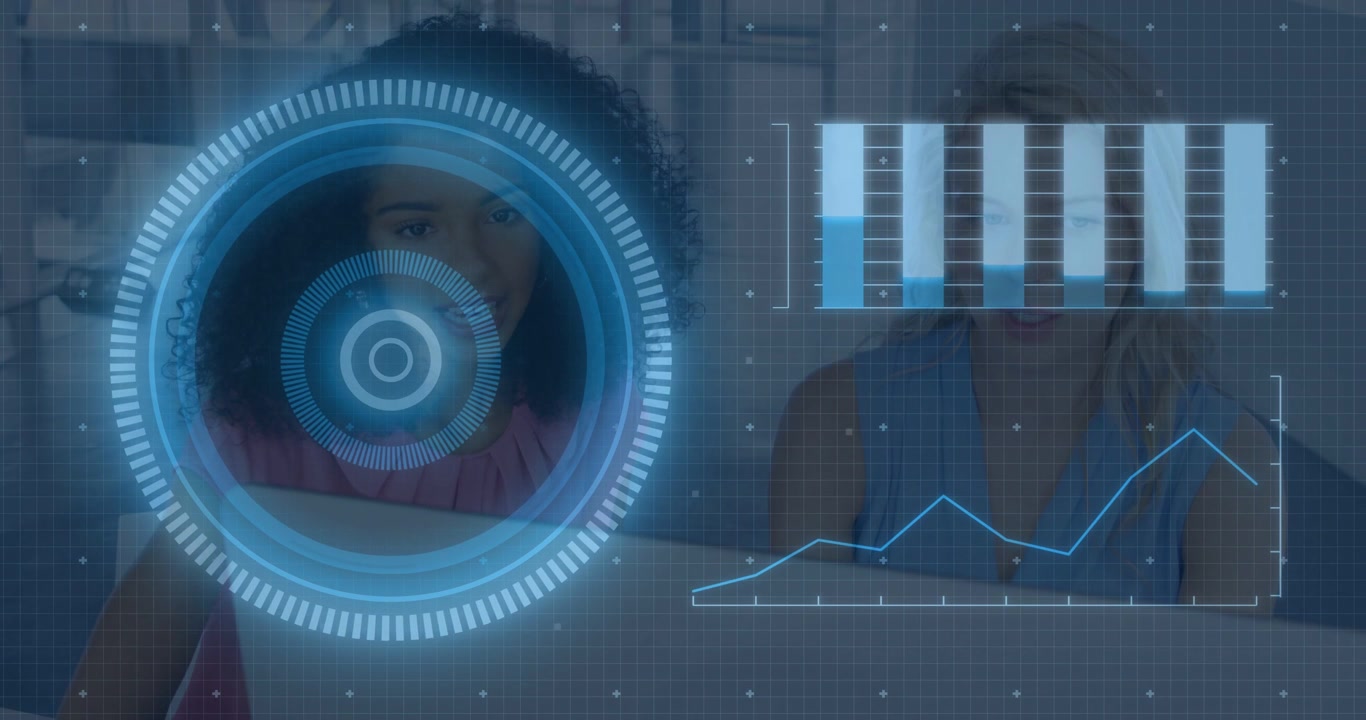 Vertical video: Two women sitting reviewing analytics on laptop HUD pulsing causing charts updating