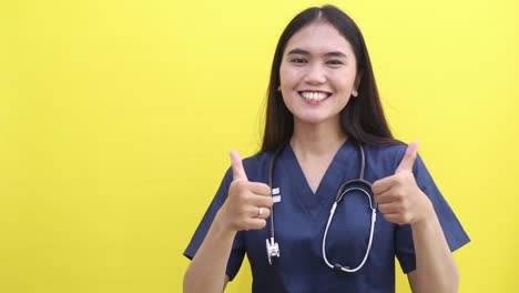 smiling young asian doctor woman standing presenting sideways and showing thumbs up