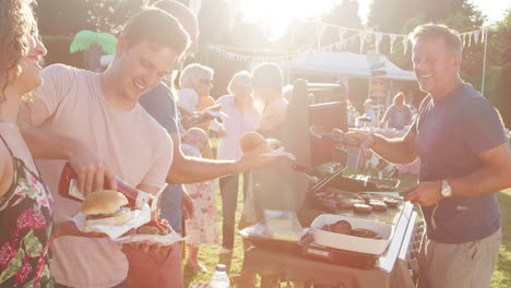 Slow-Motion-Shot-Of-Man-Serving-On-Barbeque-Stall-At-Summer-Garden-Fete