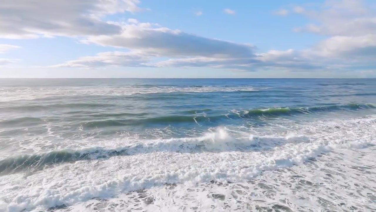 Ruhige Meereslandschaftsaufnahme von rollenden Wellen und weißem Schaum an der Pazifikküste am Khalaktyrsky-Strand, Region Kamtschatka, Russland, unter blauem Himmel.
