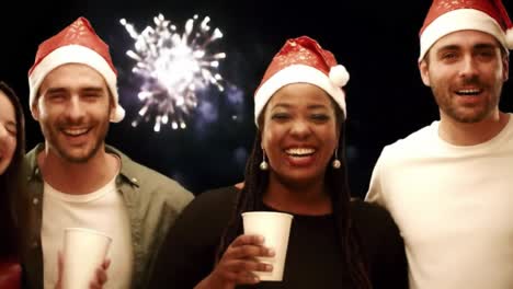 celebrating together: friends in festive hats, sharing laughter and joy amidst a sparkling background of fireworks