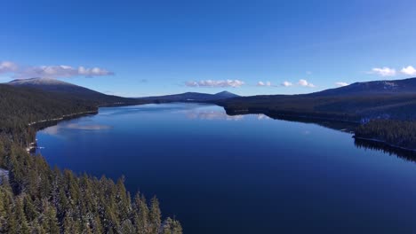 drone right to left over reflective blue lake on sunny winter day, 60fps