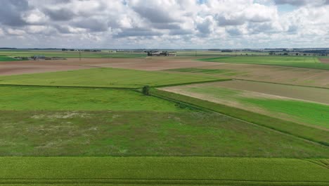 Aerial-view-of-expansive-green-fields-near-Paris,-France-under-a-cloudy-sky