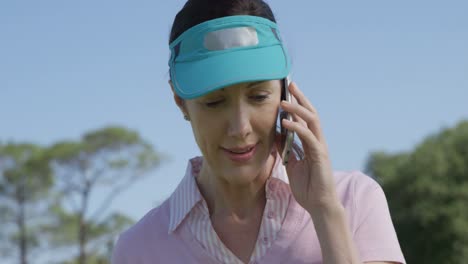 female golf player talking on mobile phone while playing golf