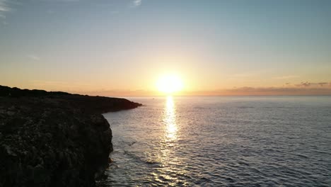 Hombre-De-Pie-En-El-Acantilado-Viendo-El-Amanecer-Sobre-El-Océano-Cerca-De-Sa-Coma-En-Mallorca,-España