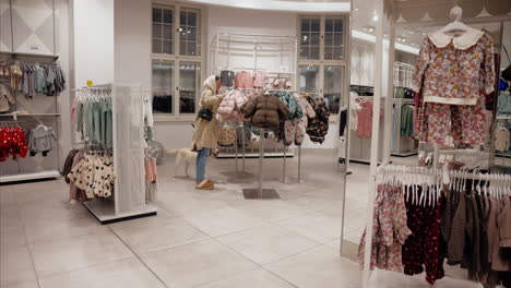 young mother with cute labrador shopping for baby clothes at a pet friendly clothing store