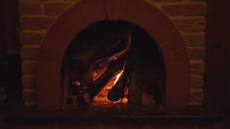 beautiful cozy fireplace with red colored brick decor with burning firewoods