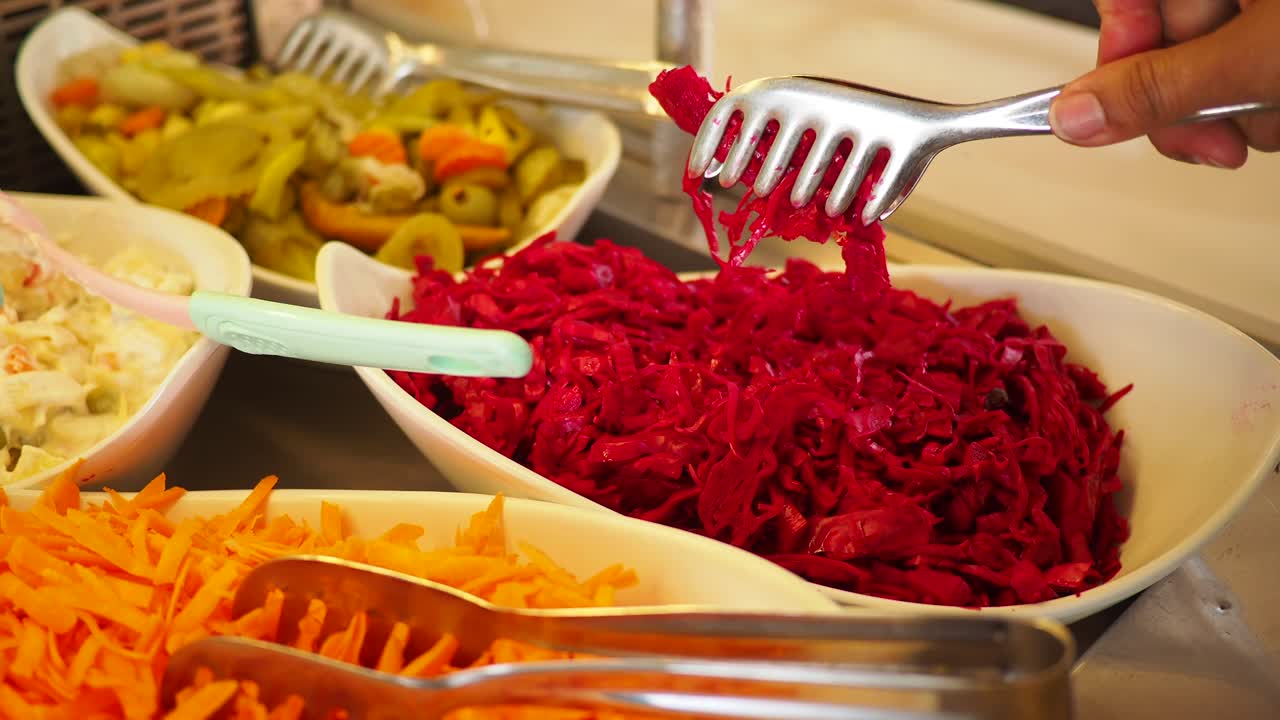Mano che serve insalata di cavolo rosso da un buffet