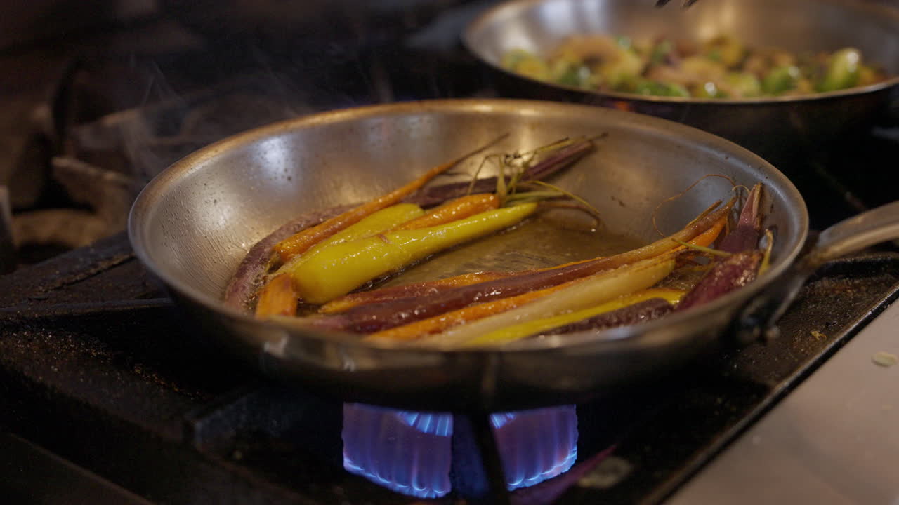 Verdure che sfrigolano in padella su un piano cottura caldo. Primo piano di una scena di cucina con vapore e condimento, che mostra verdure saltate salutari saltate in padella per un pasto fresco in cucina
