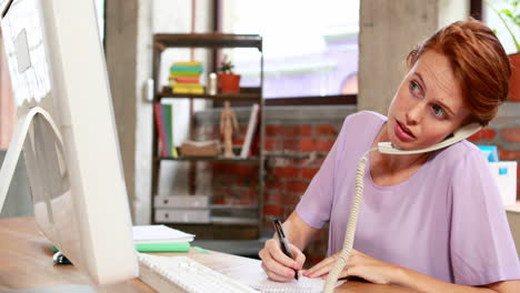 Mujer-De-Negocios-Casual-Hablando-Por-Teléfono-En-Su-Escritorio