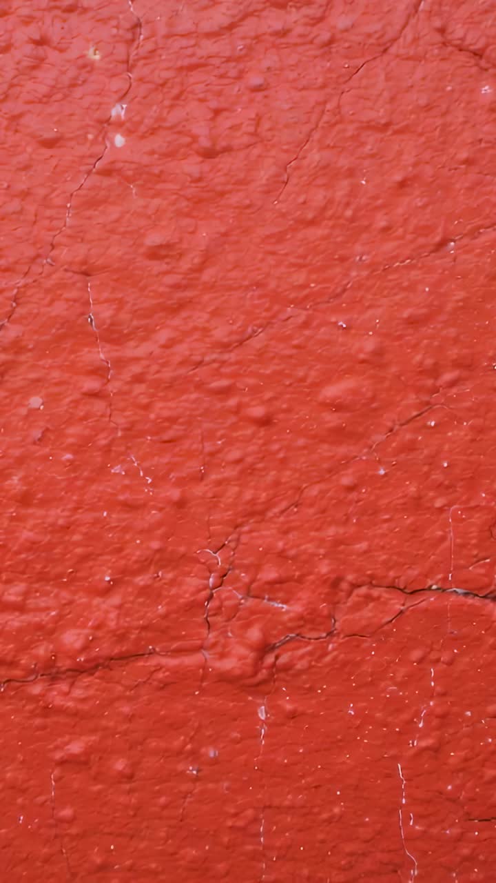 Vertical video: Sliding camera showing red plaster wall up close revealing cracks bumps seam specks