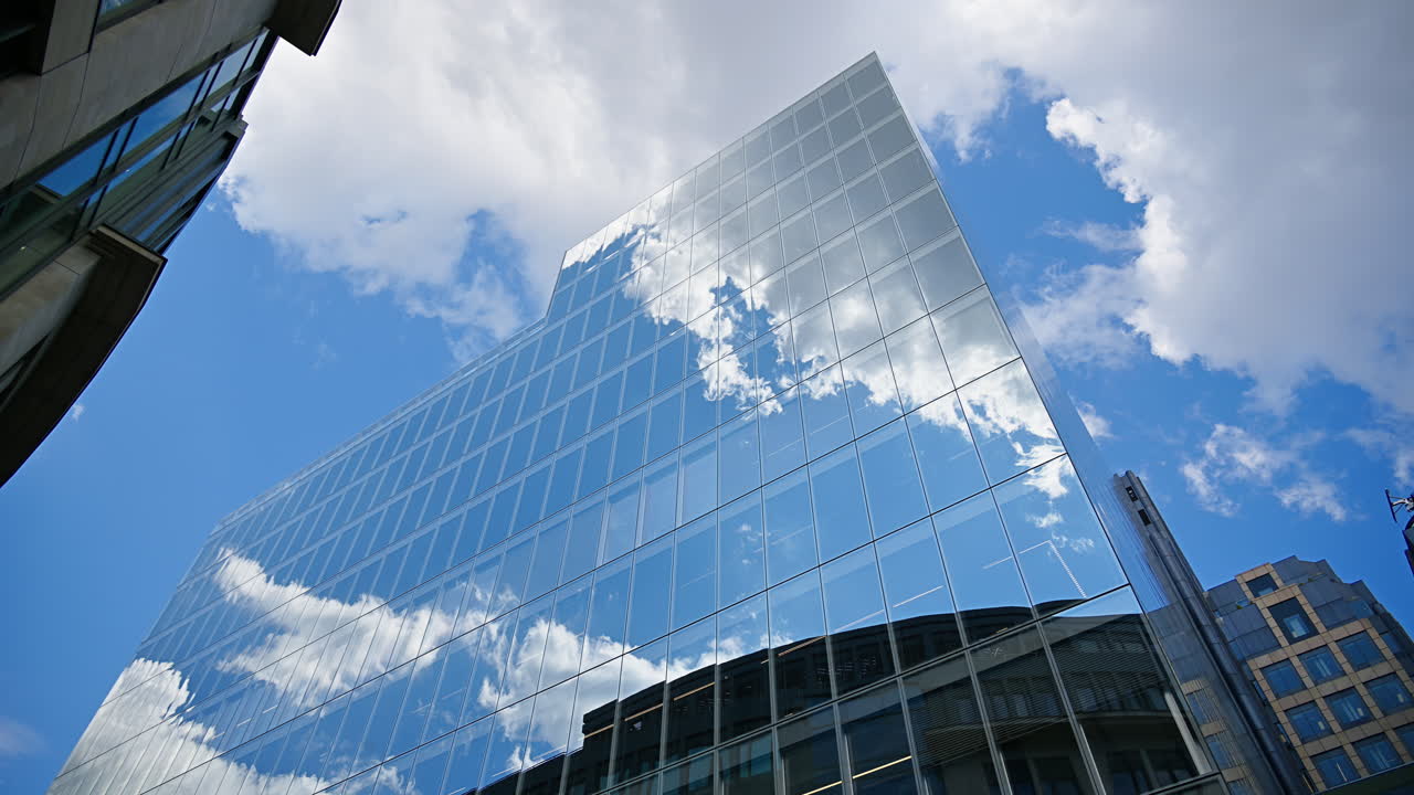 Timelapse of modern glass skyscrapers of London's financial district reflecting the blue sky next to historic architecture