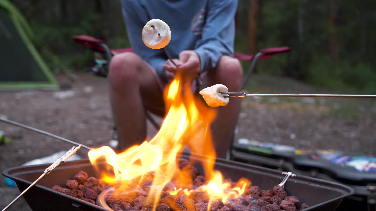 person toasting marshmallows over the fire camping. using a propane fire pit