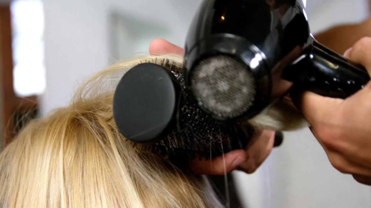 Woman getting his hair dried with hair dryer