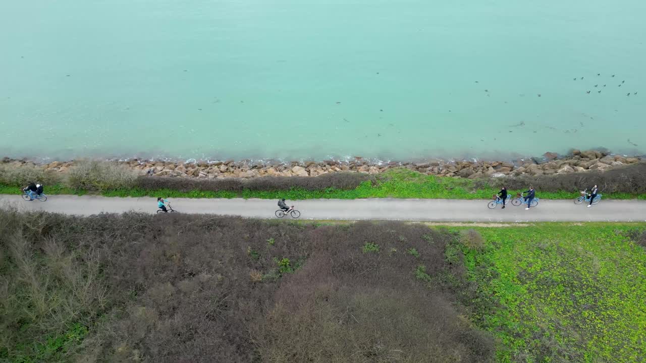 프랑스 일 드 레 섬에 있는 로익스 마을의 바다 해안 근처에서 자전거를 타는 사람들, 샷 주변의 공중 궤도