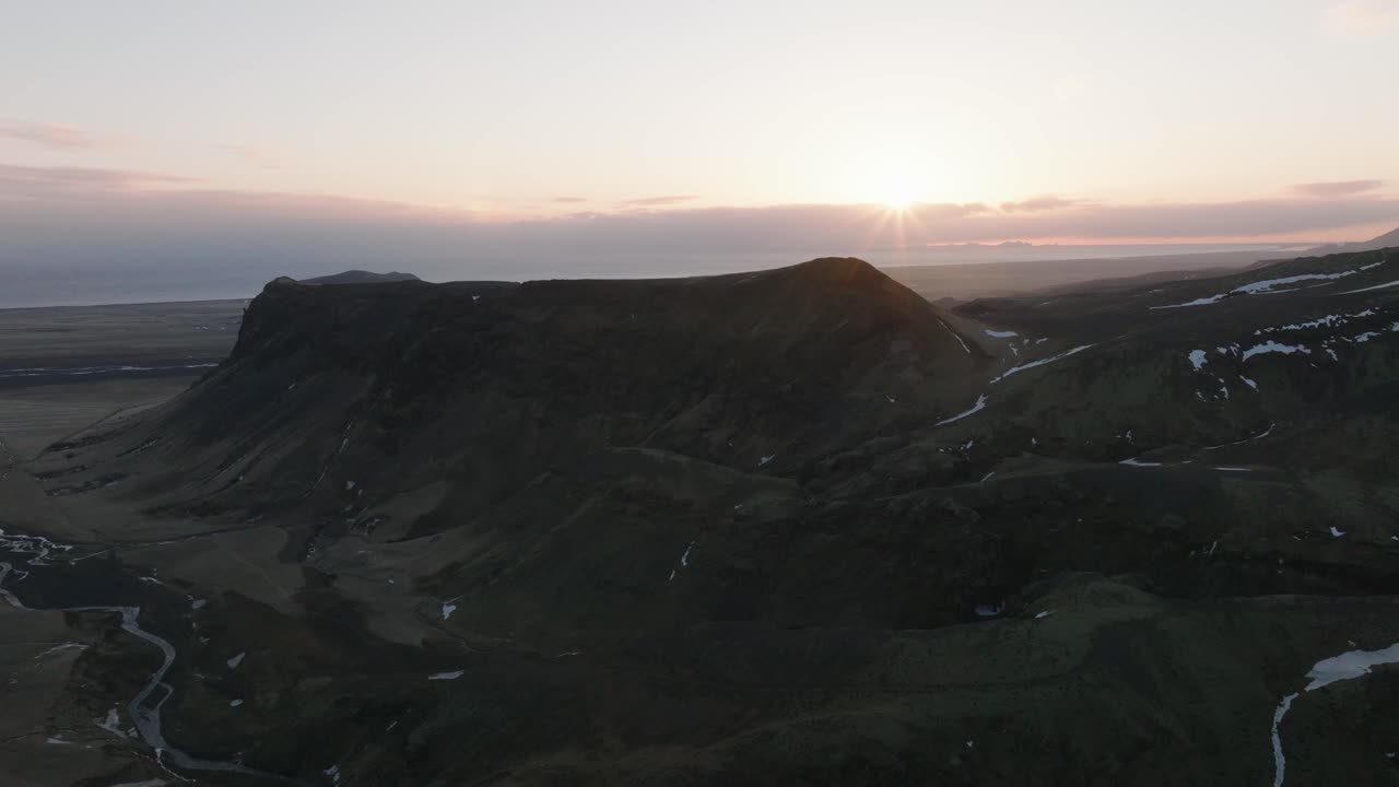 Ilmakuva maisemasta vuorenhuipuista sulavan lumen kanssa Islannissa, auringonlaskun aikaan.