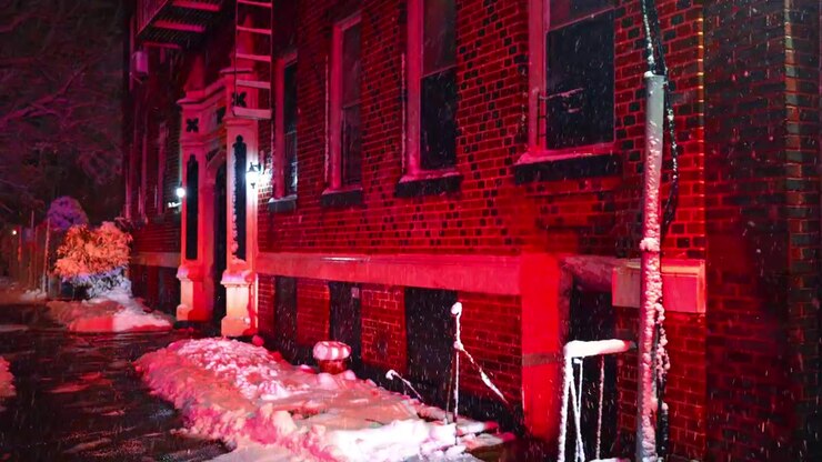 New York, USA, 20 February 2026: Utility vehicle window reflecting red emergency lights. Detailed view of a vehicle side window covered in snow and ice with red light reflections at night