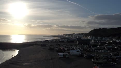 Luftaufnahme-Der-Strandpromenade-Von-Hastings-Bei-Sonnenuntergang-Mit-Fischerbooten,-Hastings-An-Der-Ostküste-Englands