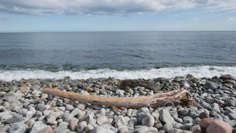 Wellen-Plätschern-Auf-Felsigen-Strand-Mit-Treibholz---Breit