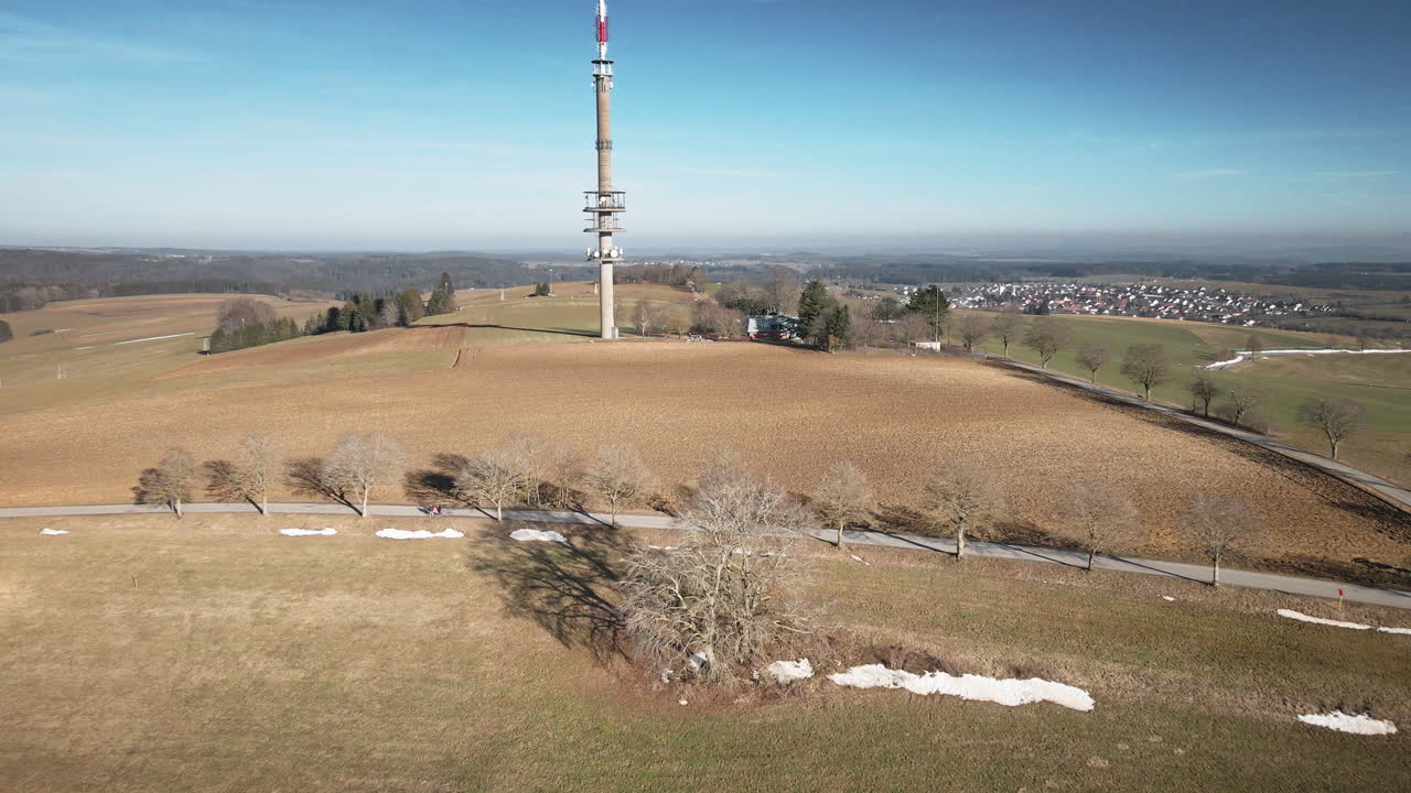 Drone 4K che si avvicina a una torre di telecomunicazioni attraverso i campi agricoli di Vitto Tuttlingen. Ripresa aerea Premium che rivela campi aridi, colline, villaggi distanti e infrastrutture. Ideale per aziende tecnologiche, agricoltura e aree rurali.