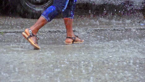 close up of legs walking through huge puddles on the street during heavy rain