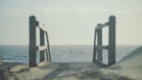 red buoy float floating in rough sea with staircase down to the beach