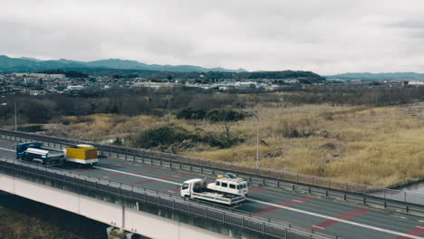 Cars-Travelling-At-Mutsumi-Bridge-With-A-View-Whale-Pond-And-Riverbank-Meadow-In-Tokyo,-Japan