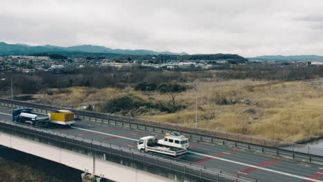 coches que viajan en el puente mutsumi con vistas al estanque de ballenas y al prado ribereño en tokio, japón