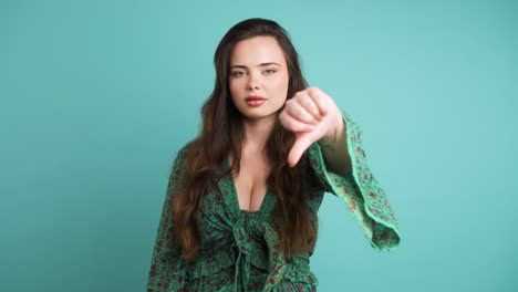 sad young woman showing thumb down in blue studio