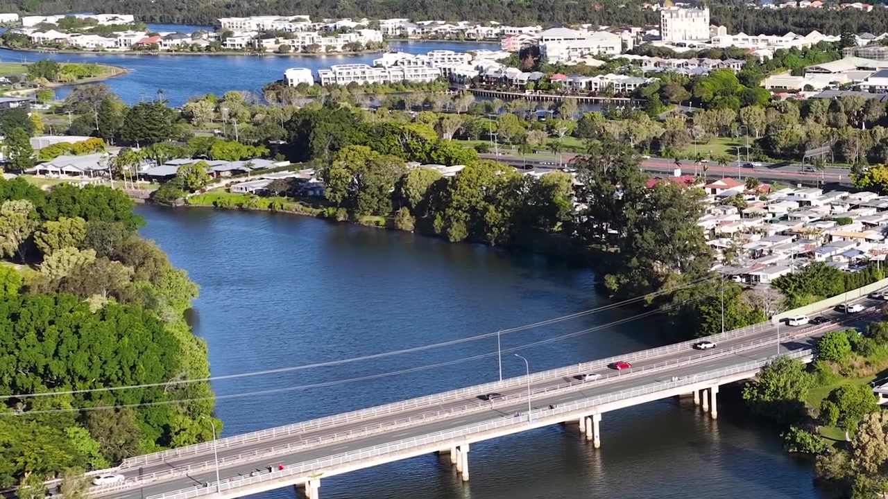 Toma aérea con dron de coches circulando por un puente sobre un río azul durante el día