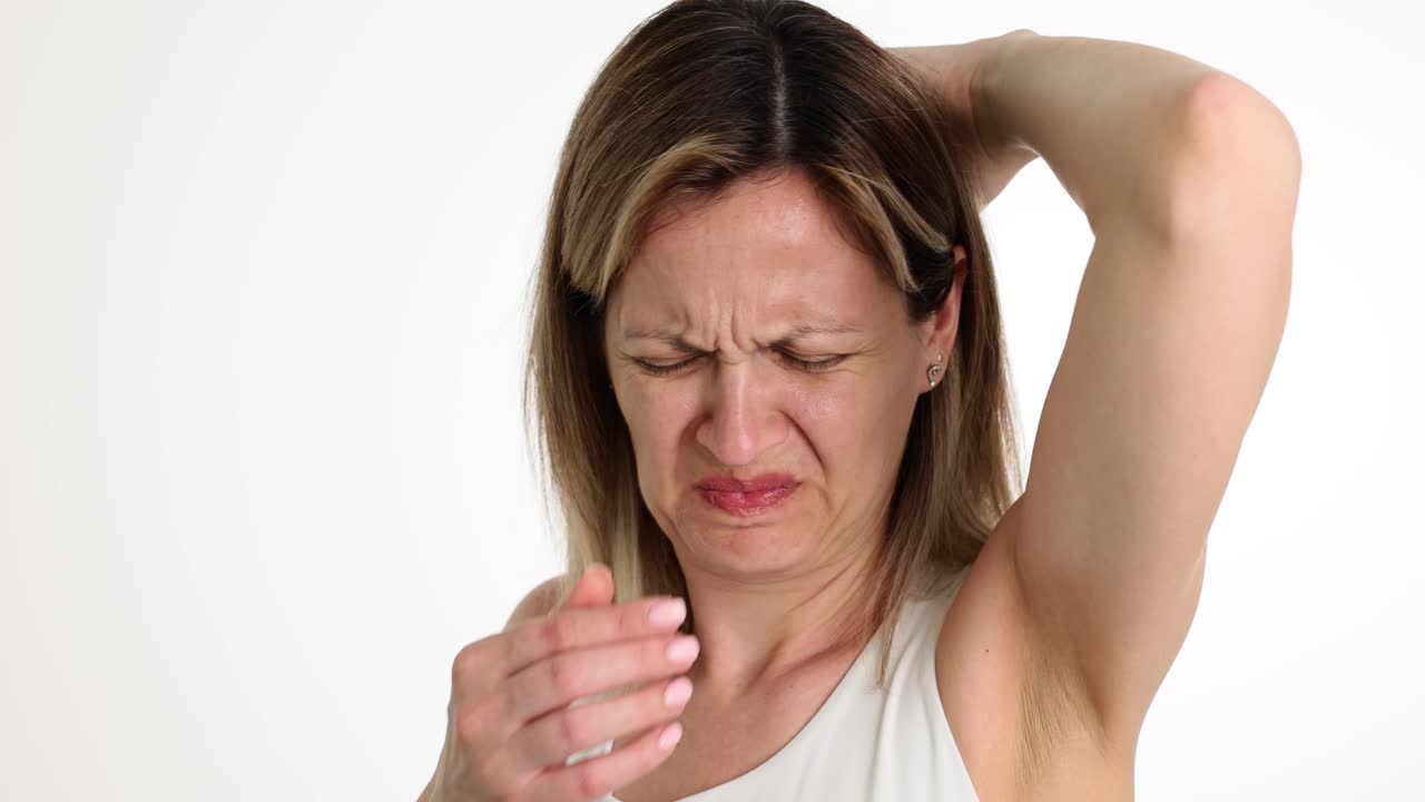 A woman expressing disgust at her own body odor